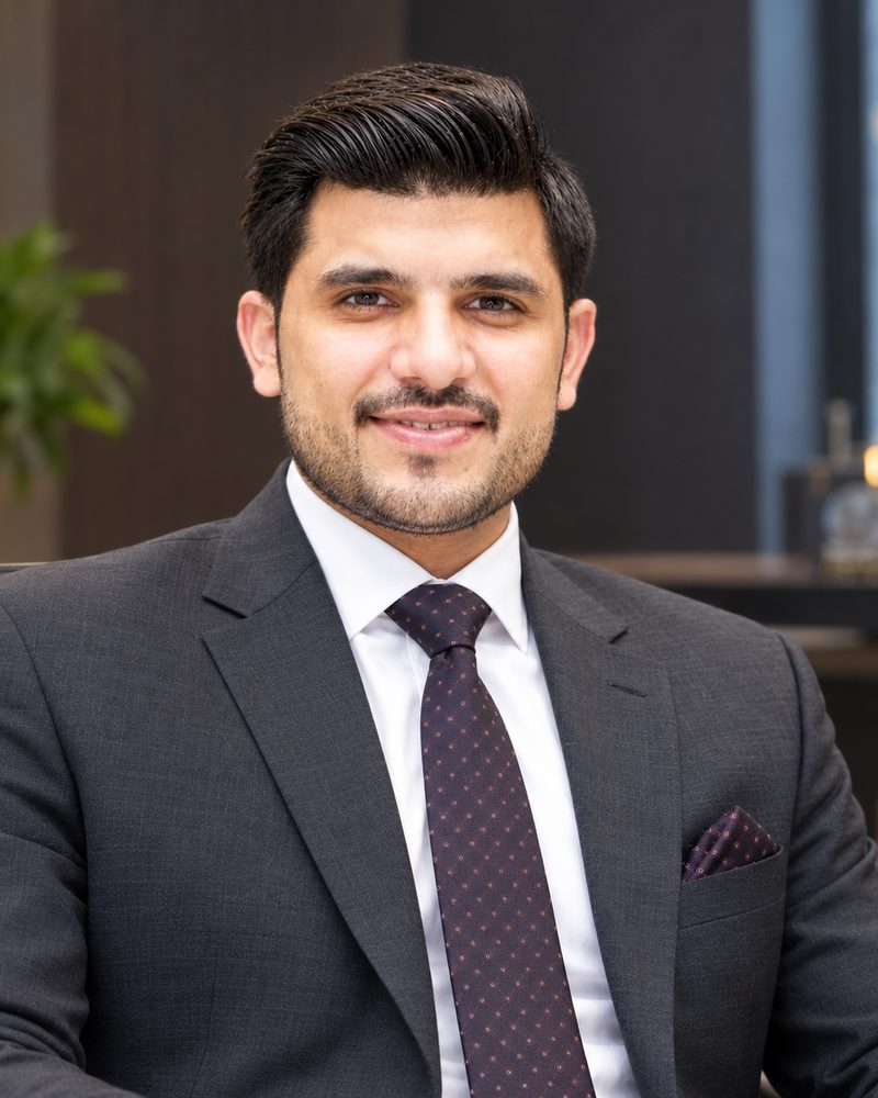 Waqas Zafar, smiling, in a suit in an office